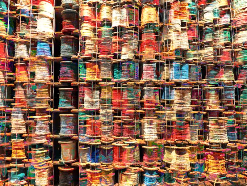 Stacks of colorful twine spools in a Manchester hotel form a grid, layered with vibrant edits